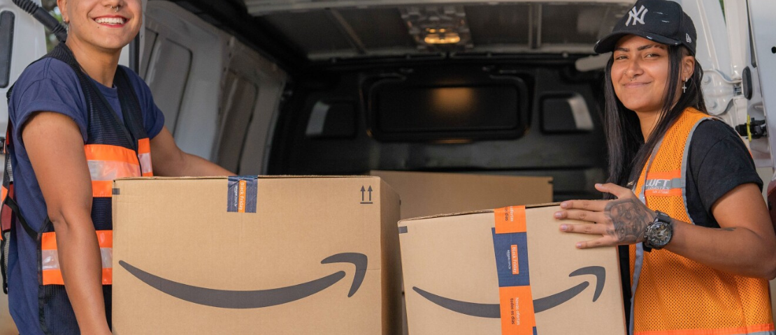 Dois entregadores da Amazon em frente a van, carregando caixas