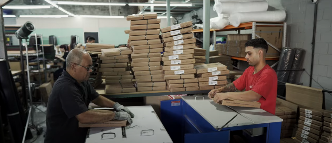 Funcionários da Eddias embalando pedidos em galpão logístico, representando a eficiência operacional da empresa no e-commerce.